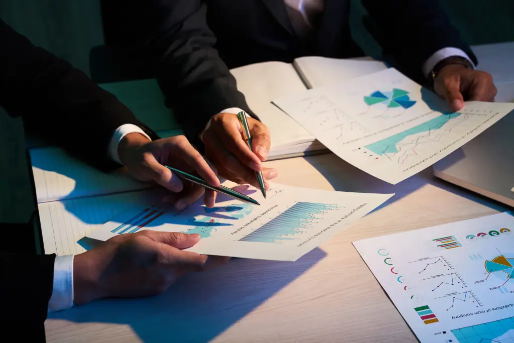 Two colleagues reviewing printed management report charts with pens